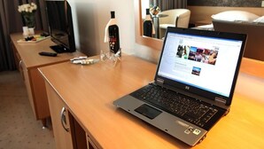 A hotel room with a wooden desk, a laptop, a bottle of wine, and a remote control. - Hotel Zovko (Zagreb)
