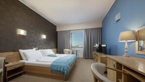 A hotel room with a bed, a desk, a chair, a TV, and a window with curtains. - Hotel Zovko (Zagreb)
