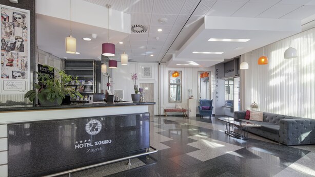 A hotel lobby with a reception desk, seating area, and a check-in counter. - Hotel Zovko (Zagreb)