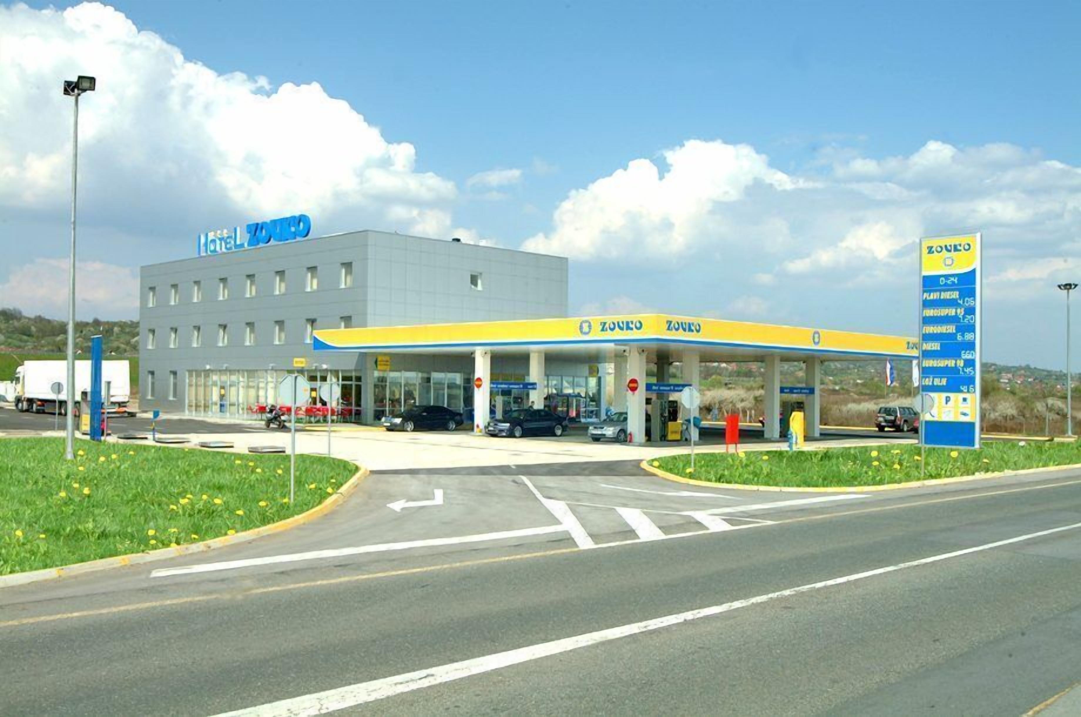 Hotel con una gasolinera anexa, mostrando un cielo despejado y una carretera al frente.