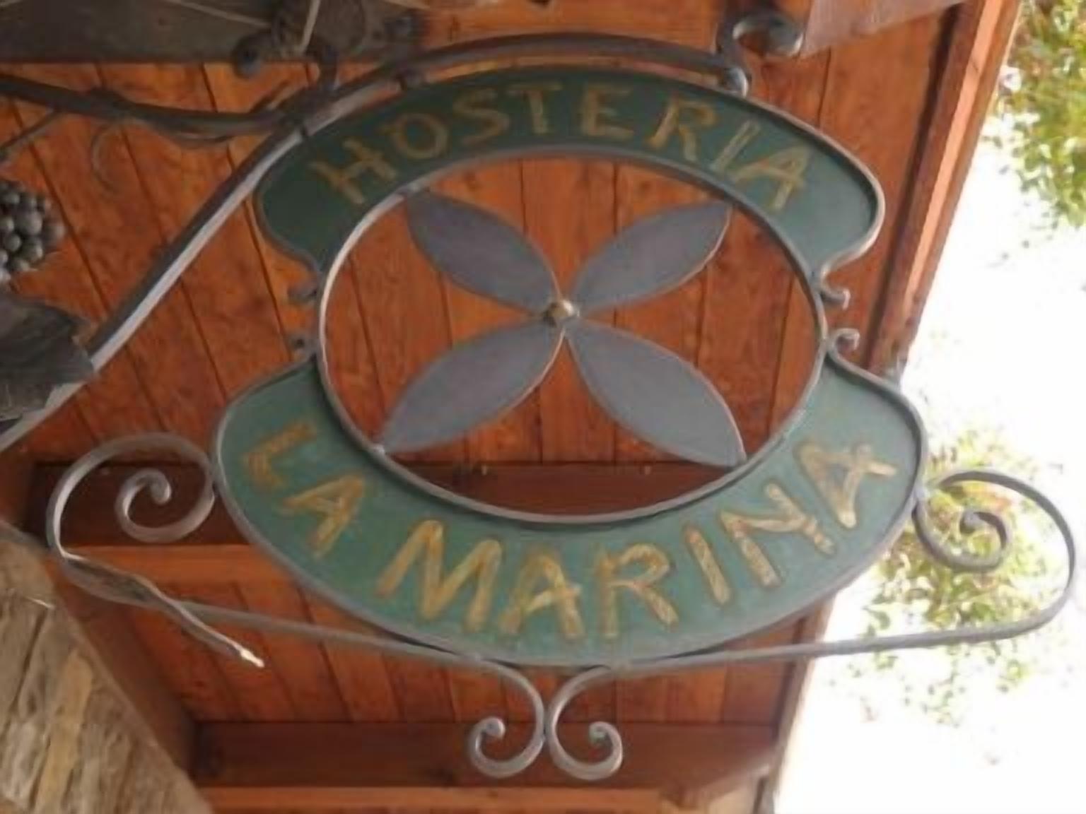Une plaque métallique portant l’inscription « HOSTERIA LA MARINA », indiquant la présence d’une marina ou d’un établissement situé au bord de l’eau.
