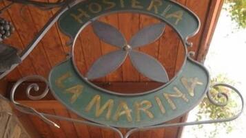 Une plaque métallique portant l’inscription « HOSTERIA LA MARINA », indiquant la présence d’une marina ou d’un établissement situé au bord de l’eau.