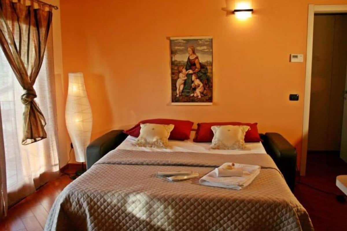 Une chambre d’hôtel avec un lit, un tableau au mur, une lampe et une porte.
