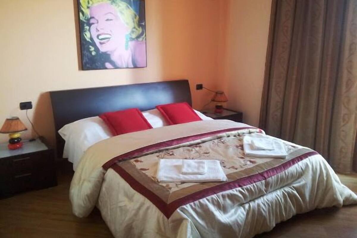 Une chambre d’hôtel avec un lit, une table de chevet, une lampe et un tableau au mur.