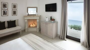 Un dormitorio con cama, chimenea, televisión y vistas al exterior.