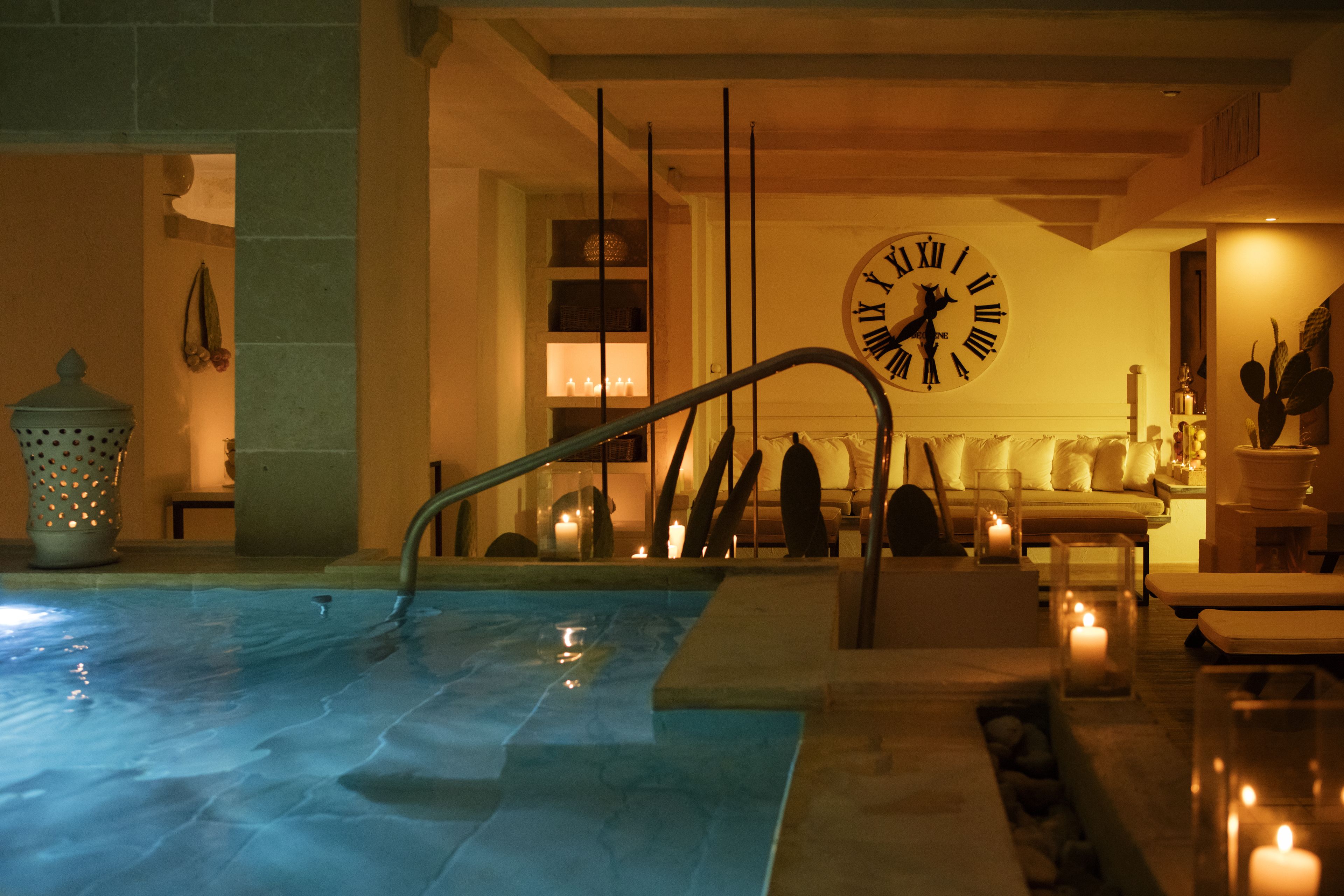 A spa area with a pool, a clock, and a seating area with candles.