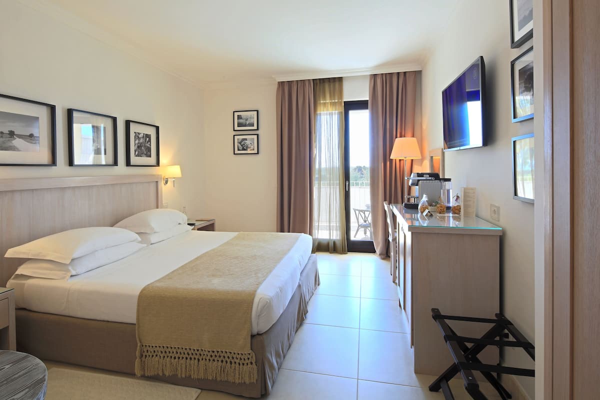 Une chambre d’hôtel équipée d’un lit, d’une table de chevet, d’une lampe, d’une télévision et offrant une vue sur l’extérieur.