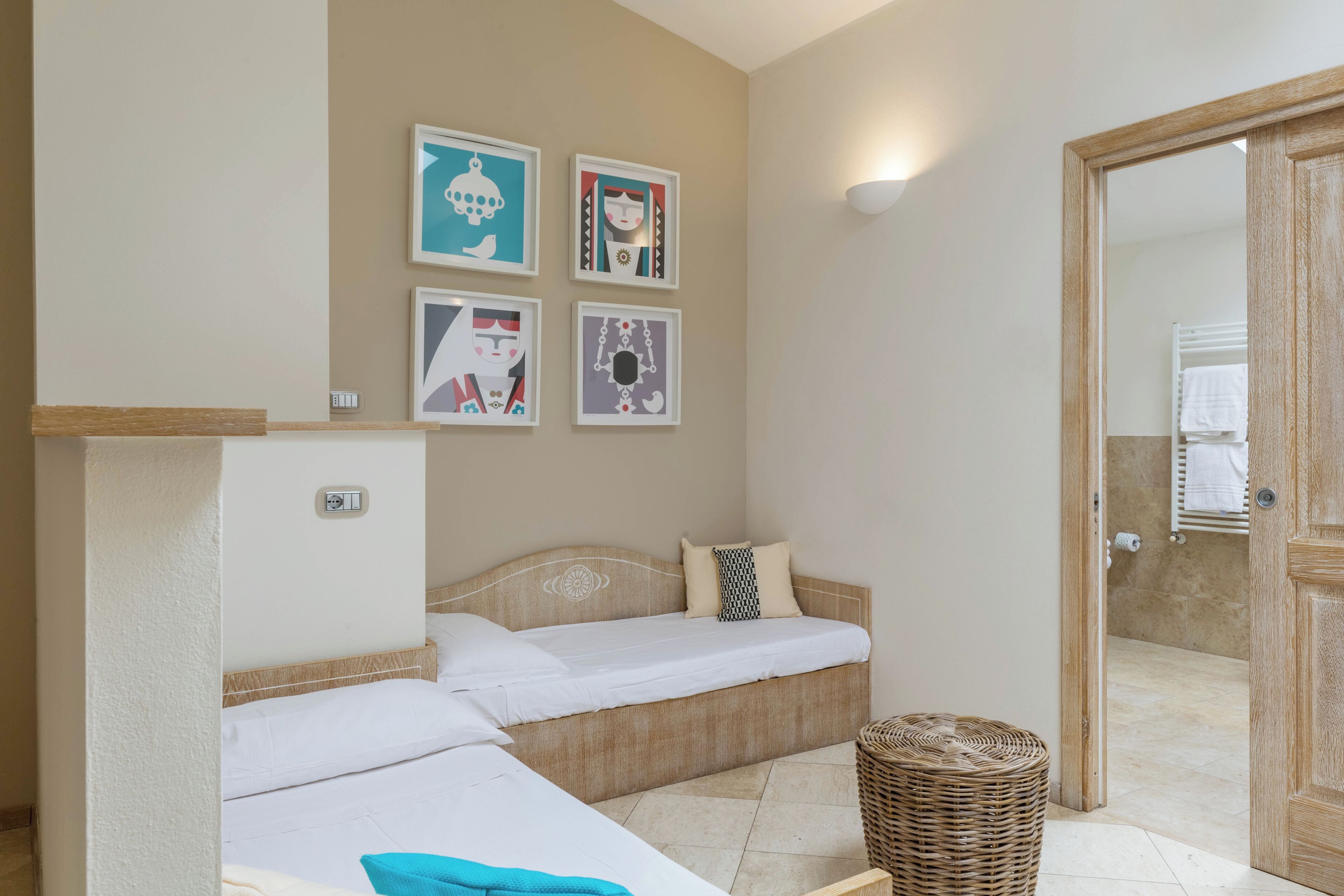 Une chambre d’hôtel avec deux lits, une lampe fixée au mur et une porte donnant sur la salle de bain.