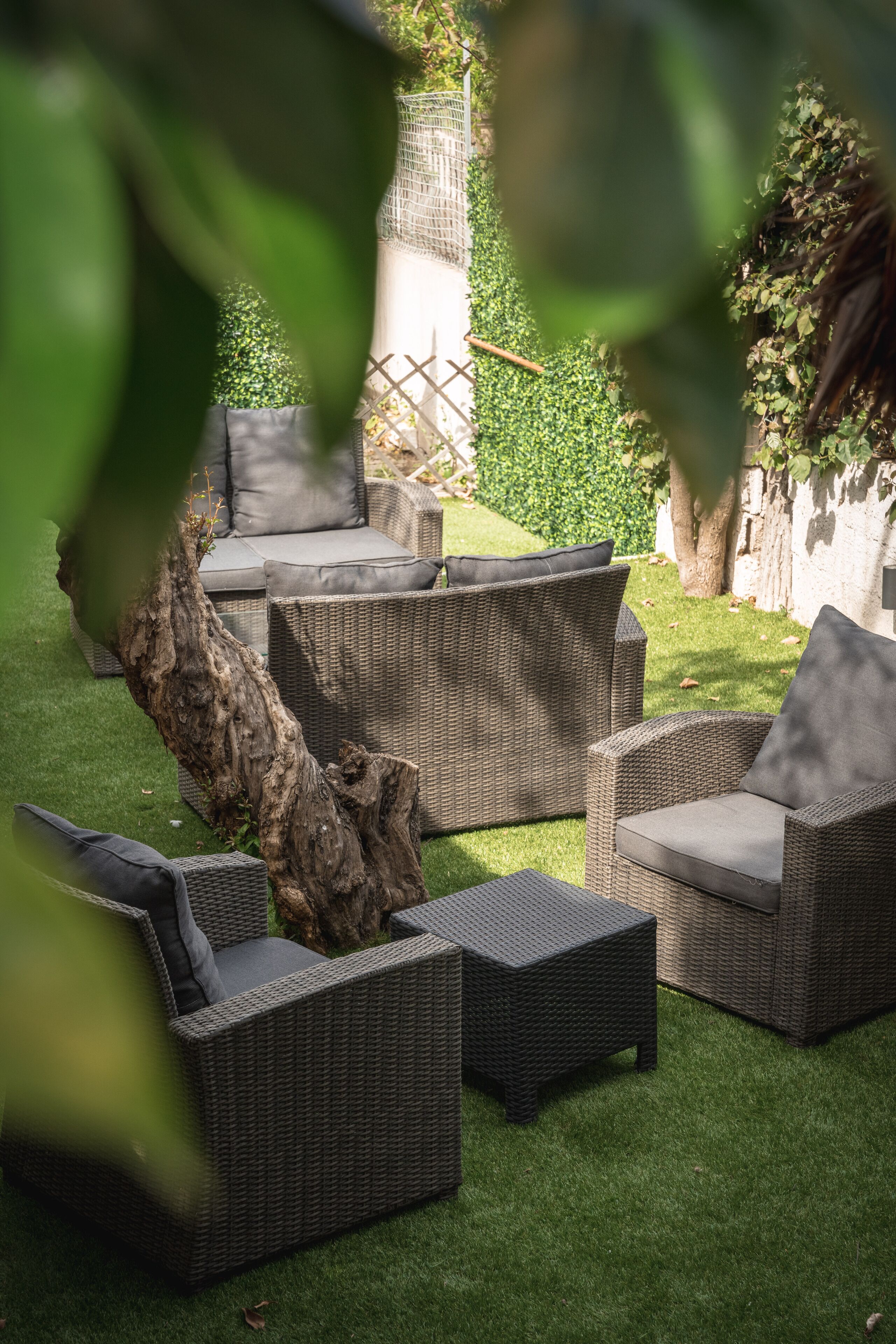 A patio area with wicker furniture and a tree stump centerpiece.