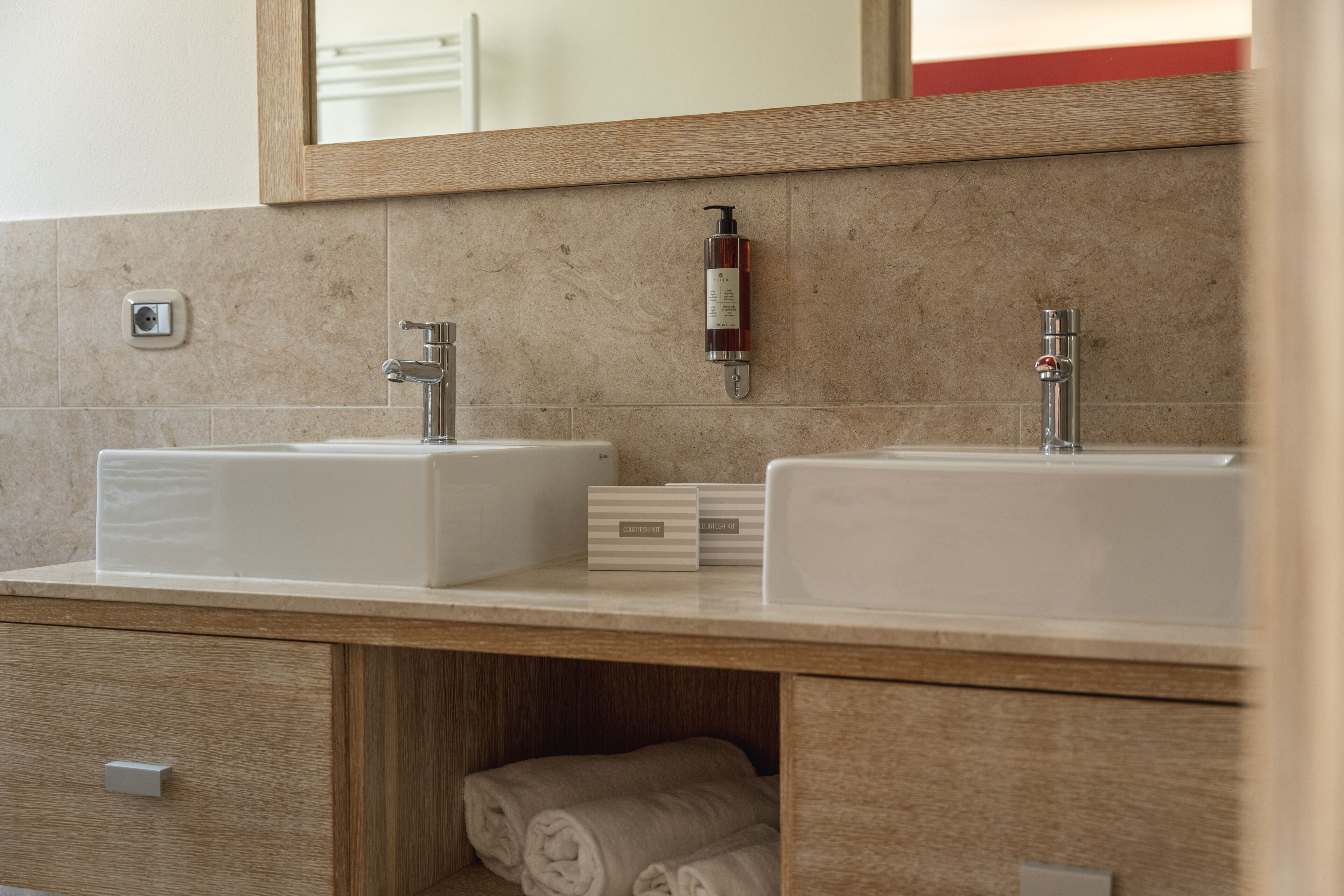 Un bagno con due lavandini, uno specchio e un portascopevoli.