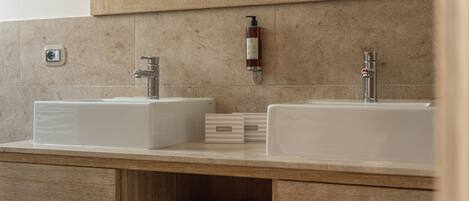Un baño con dos lavamanos, un espejo y un perchero para toallas.