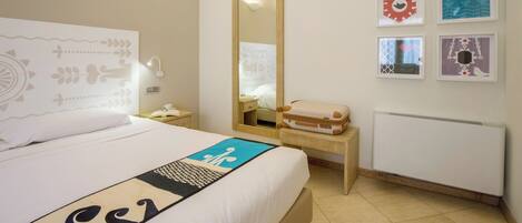 A hotel room with a bed, a bedside table, a mirror, a radiator, and wall art.