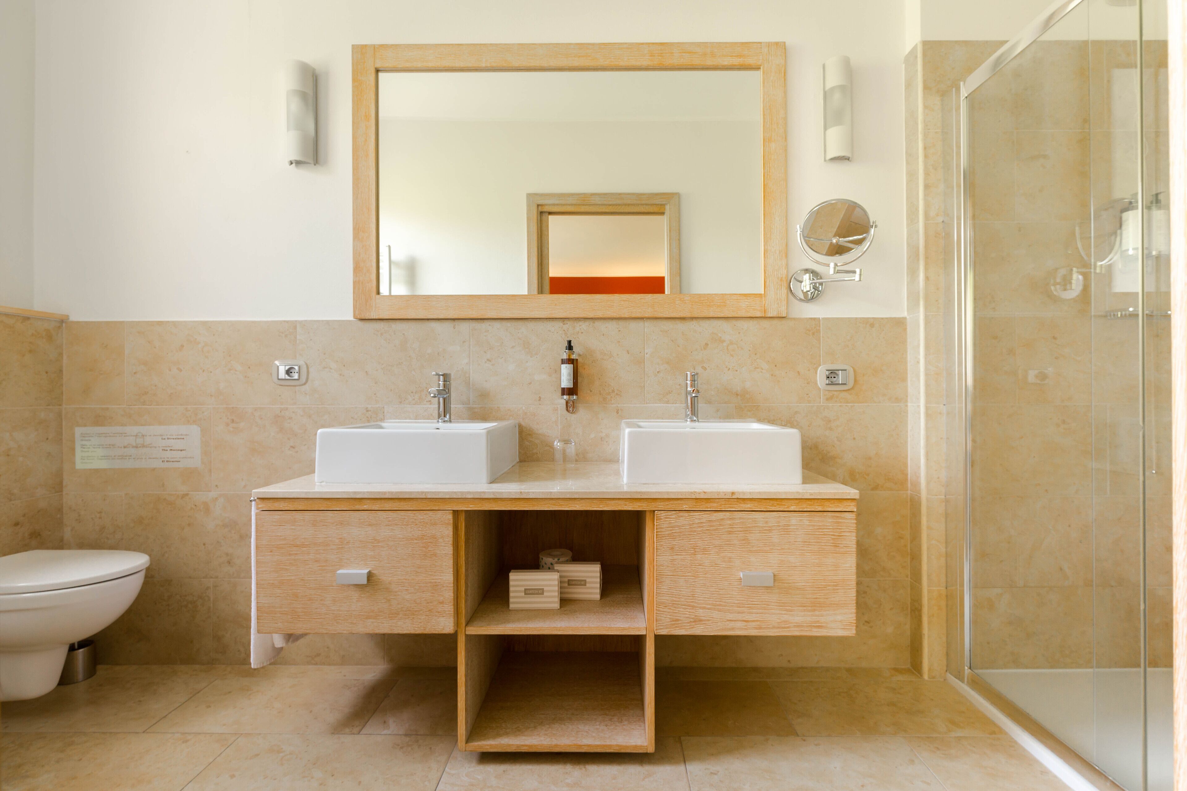 A modern bathroom with two sinks, a mirror, and a shower.
