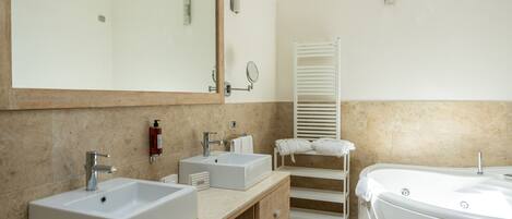 Un baño moderno con dos lavamanos, un espejo grande, un perchero para toallas y una bañera.