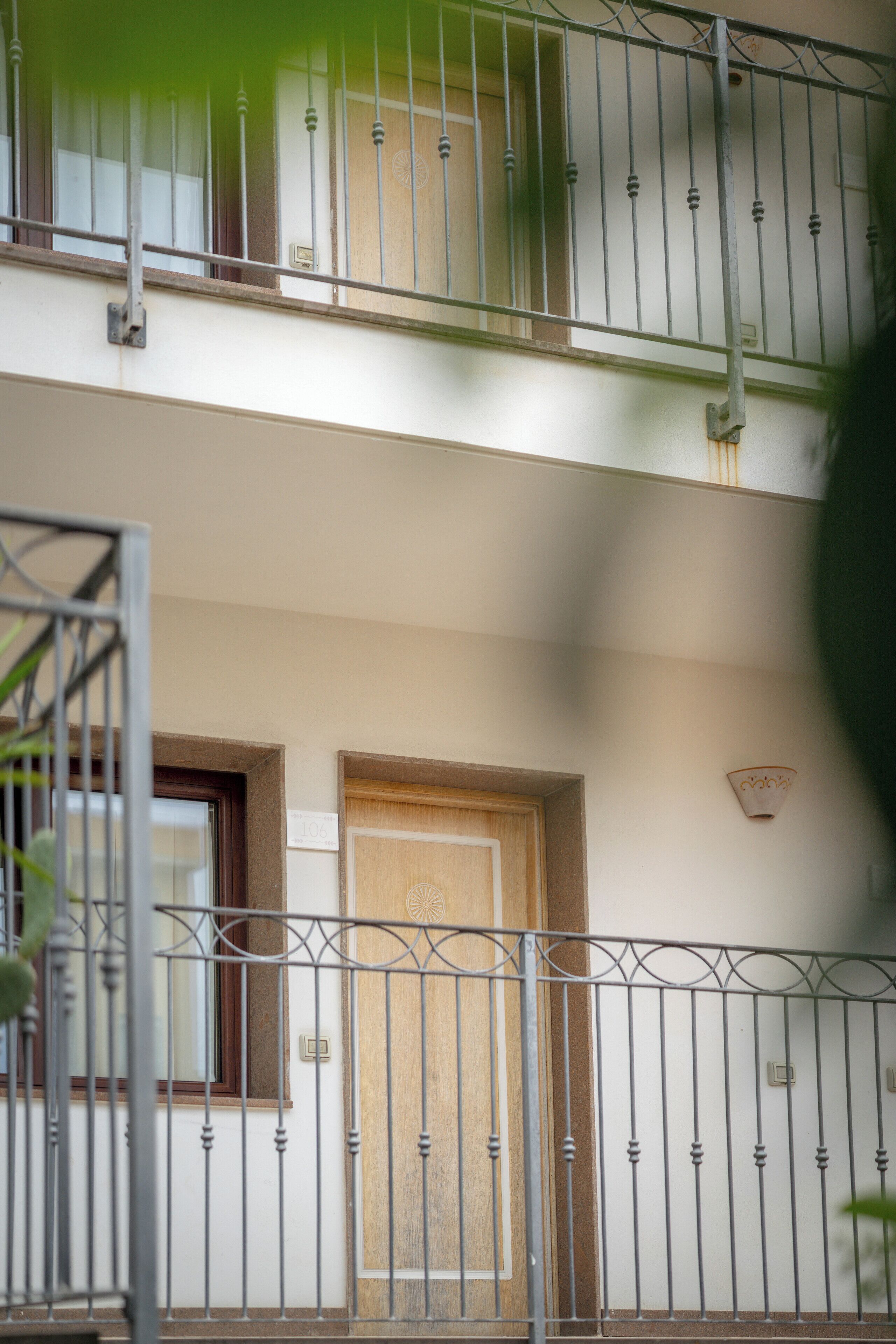 A two-story building with a balcony, a wooden door, and a metal railing.