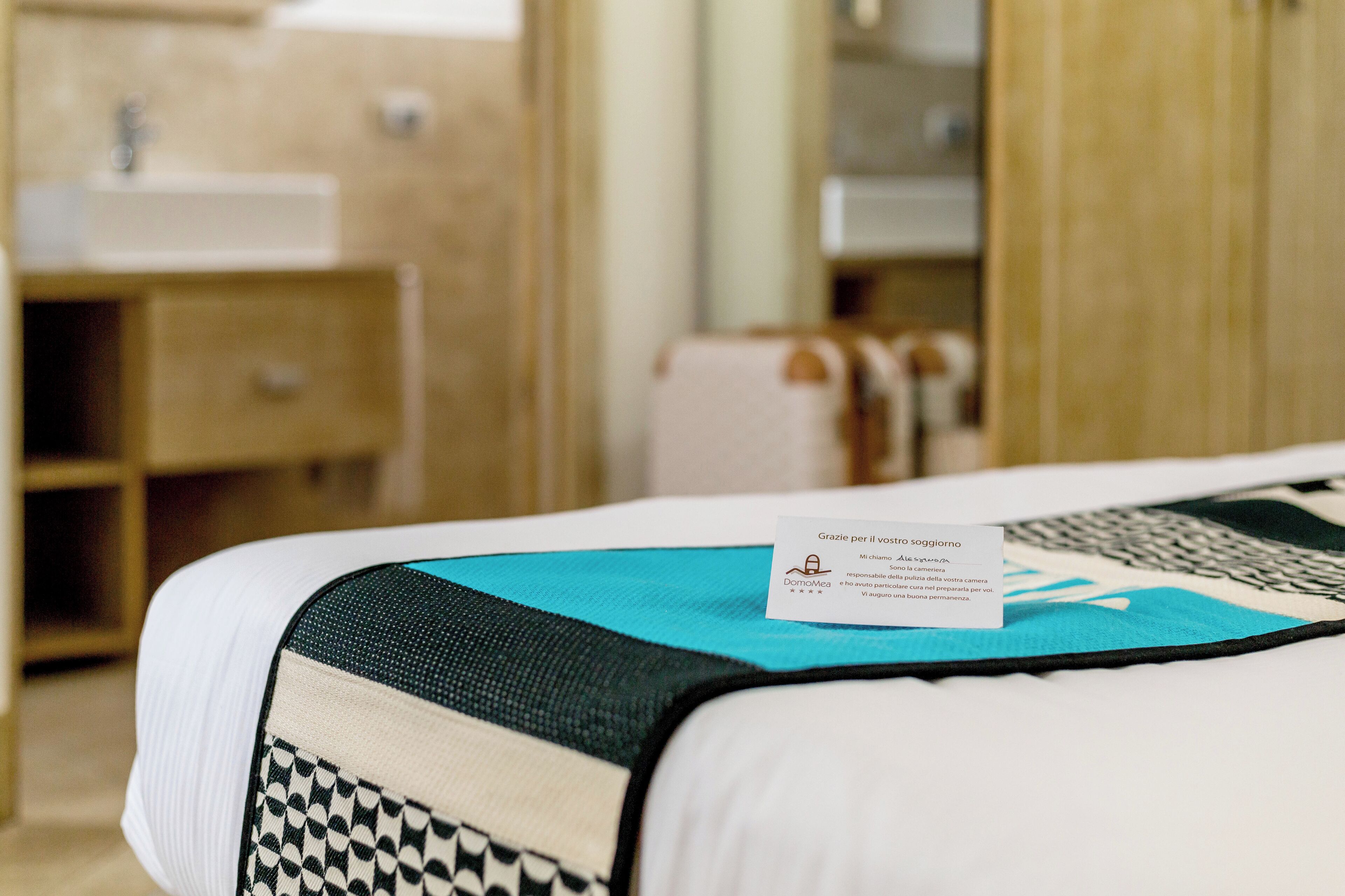 A hotel room with a bed, a bedside table, a small cabinet, and a mirror.