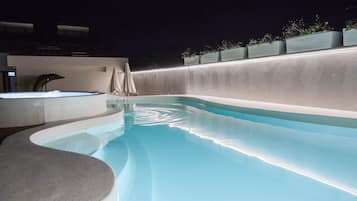 A swimming pool with a curved edge, a hot tub, and a covered seating area.