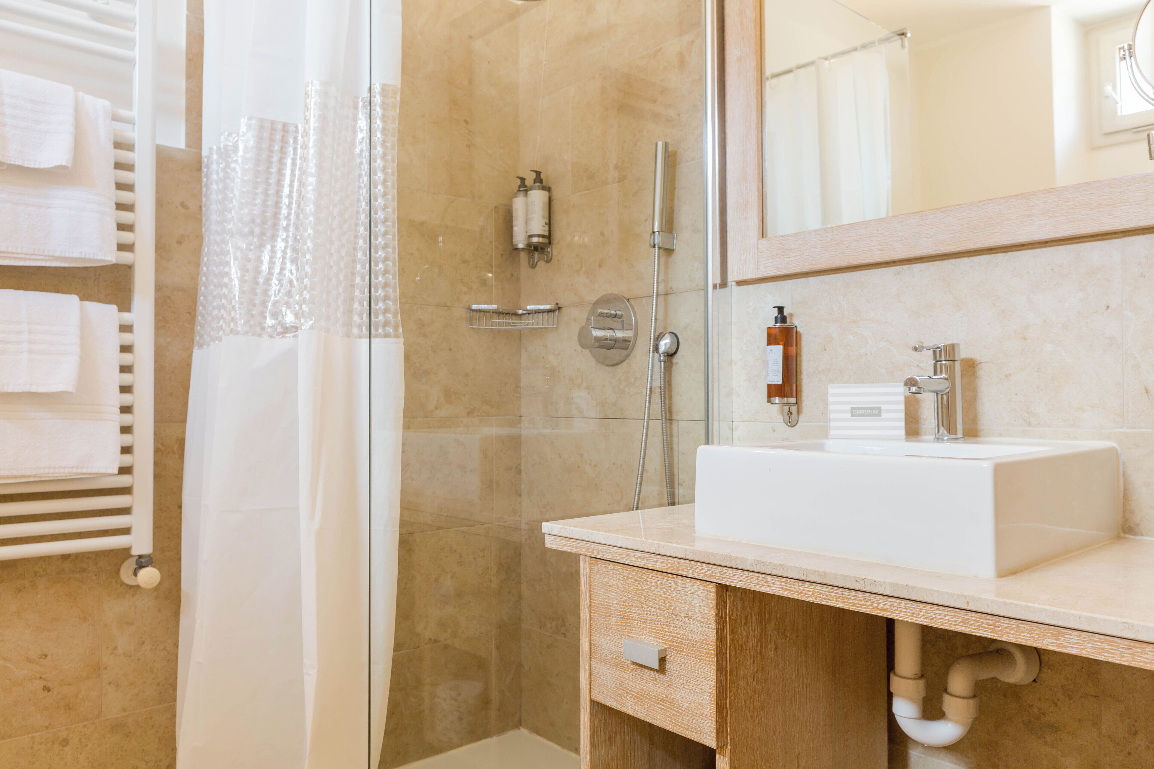 A modern bathroom with a glass shower enclosure, a white sink, and a wooden vanity.