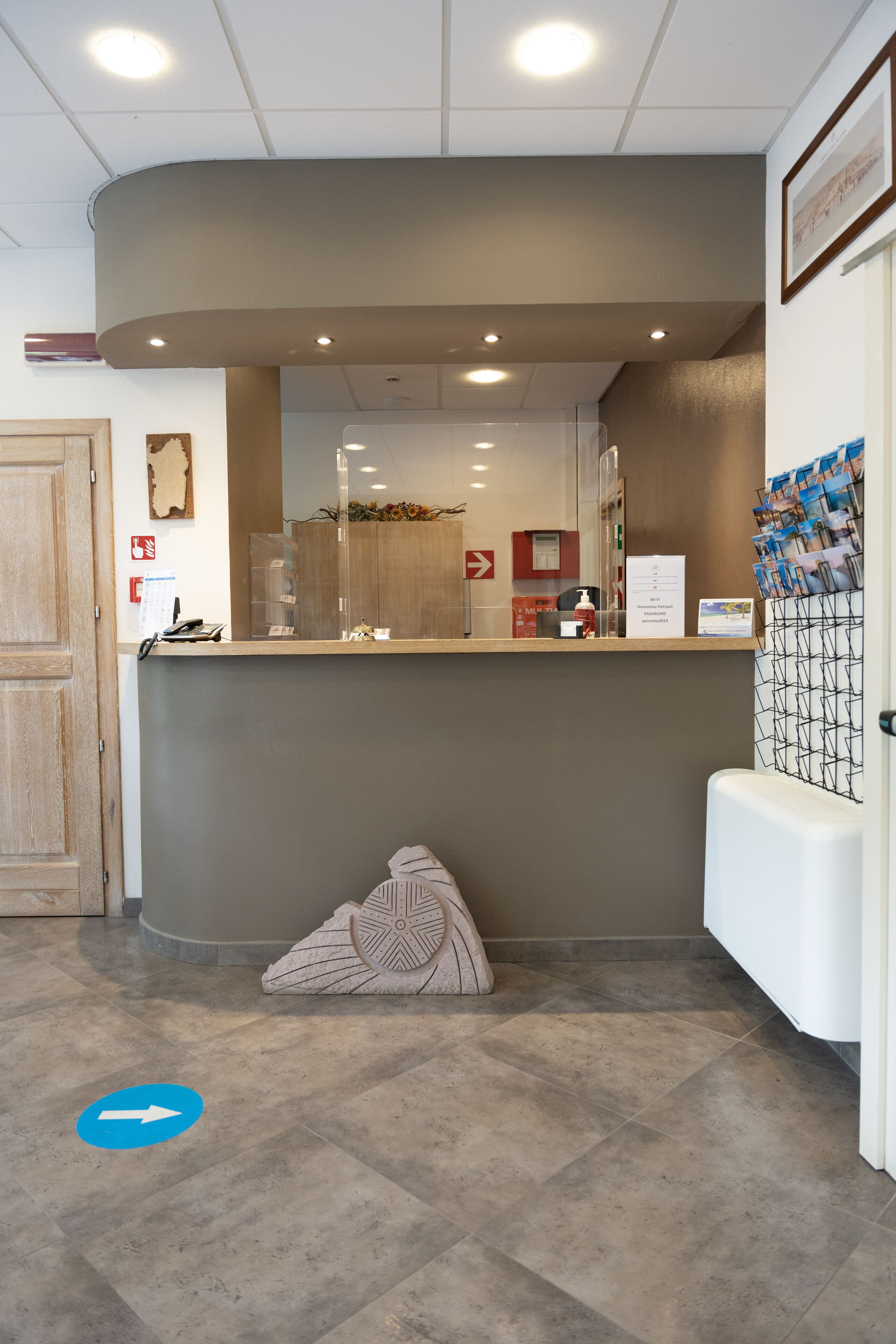 A reception area with a counter, a waiting area with a bench, and a door to the left.