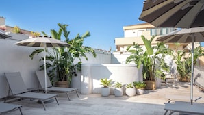 A rooftop patio with lounge chairs, umbrellas, and potted plants. - Hotel Domomea (Alghero)