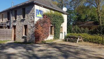 Un bâtiment en pierre avec une enseigne bleue, une clôture en bois et une allée gravillonnée.