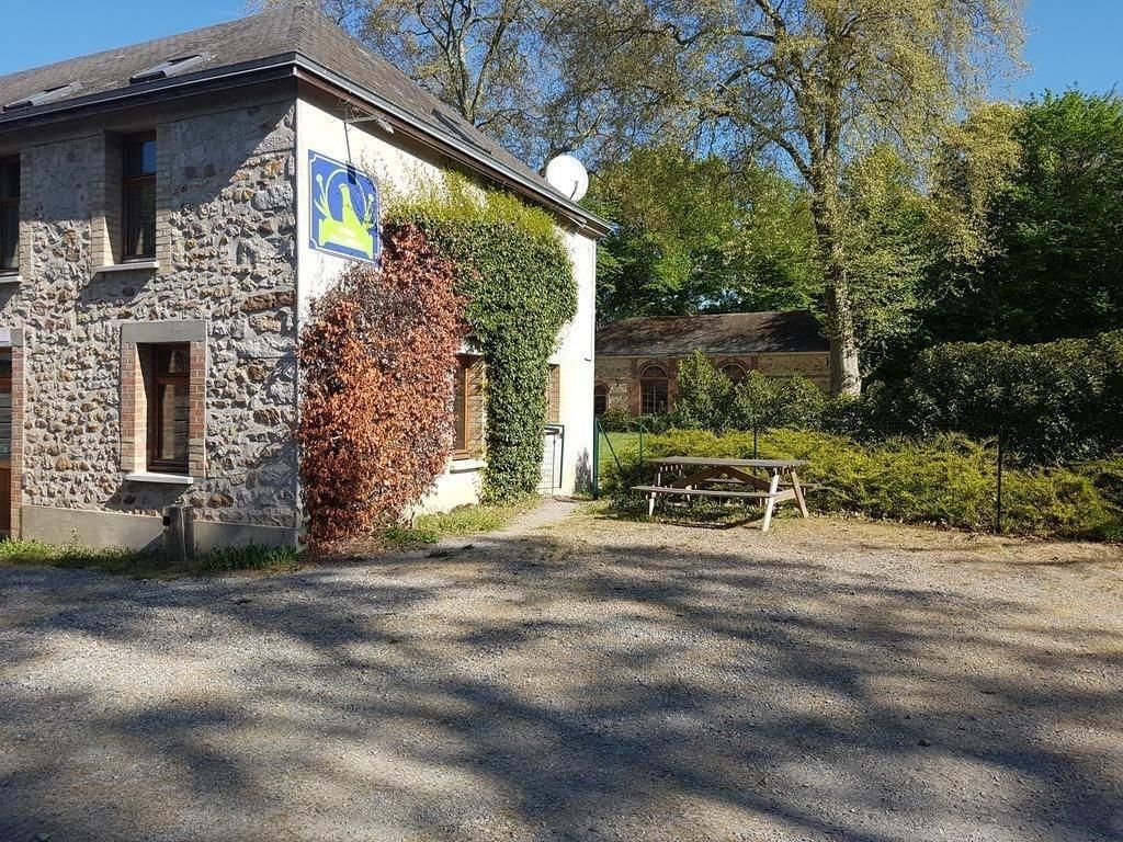 A stone building with a flag, a picnic table, and a gravel driveway.