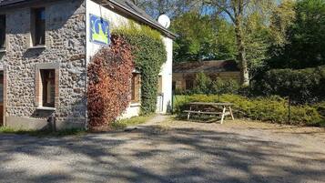 A stone building with a flag, a picnic table, and a gravel driveway.