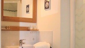 Un baño con tocador de madera, un lavamanos, un espejo y una toalla colgada en la pared.