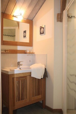 A bathroom with a wooden vanity, a sink, a mirror, and a towel hanging on the wall. - Relais des Caillères (Saint-Pavace)