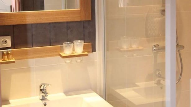 Un baño con tocador de madera, espejo, cabina de ducha de vidrio y lavamanos.