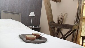 Una cama con una bandeja de cuencos, una lámpara y una estructura de madera frente a una pared gris.