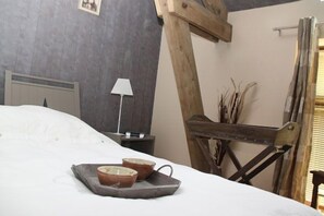 A bed with a tray of bowls, a lamp, and a wooden structure against a grey wall. - Relais des Caillères (Saint-Pavace)