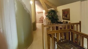 A staircase with wooden railings leading to a landing. A potted plant is on the landing, and a framed picture hangs on the wall. - Relais des Caillères (Saint-Pavace)