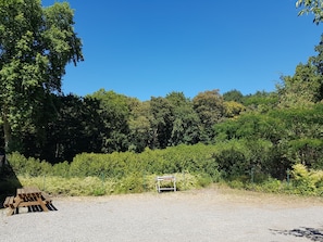 Un espacio con grava, una mesa de picnic de madera y un buzón.