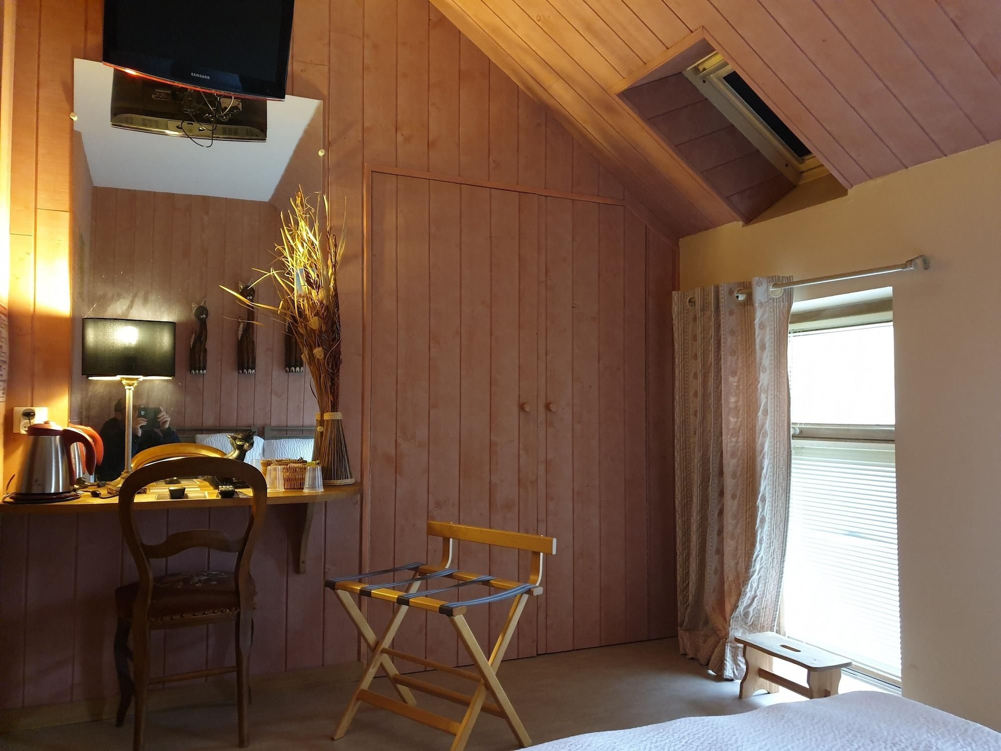 Une pièce chaleureuse avec des murs en bois, un lit, un bureau avec une lampe, une chaise et une fenêtre avec des rideaux.
