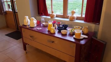 Un comptoir de cuisine avec divers aliments pour le petit-déjeuner et une fenêtre avec des rideaux.