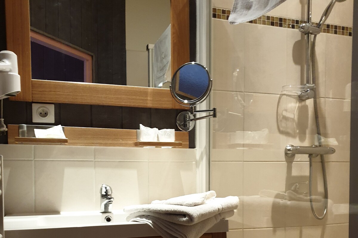 Un bagno con un mobile bagno in legno, uno specchio, un lavabo e una doccia.