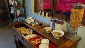 A buffet setup with various food items, a toaster, and a cereal dispenser. - Relais des Caillères (Saint-Pavace)
