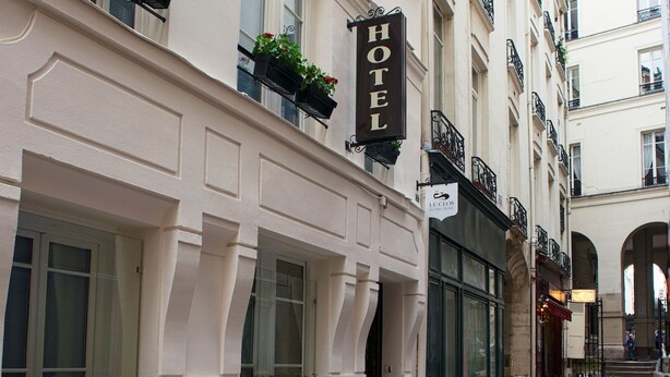 Un hotel con un cartel, plantas en macetas y una calle adoquinada.