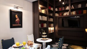 Un comedor con una mesa dispuesta para el desayuno, una estantería y una obra de arte enmarcada en la pared.