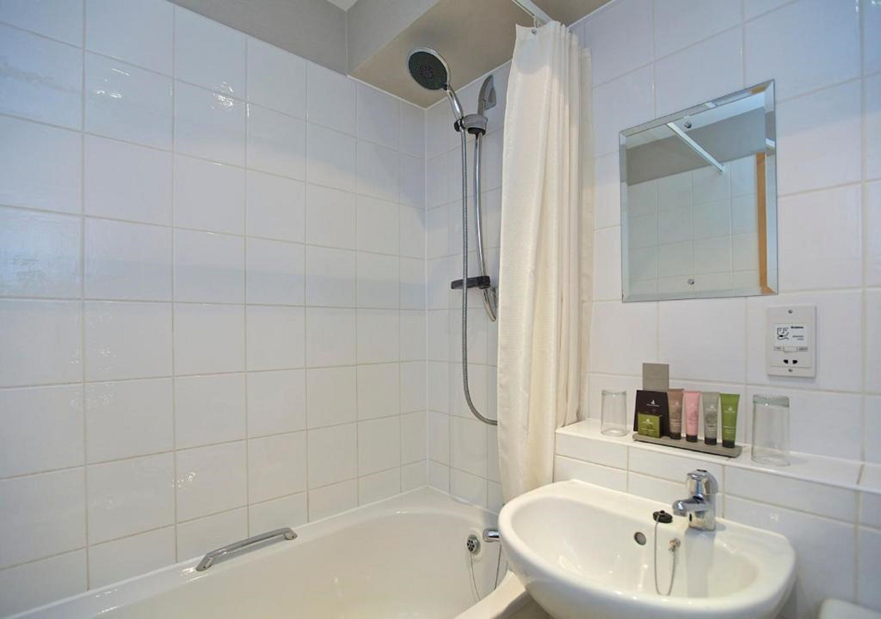 Ein Badezimmer mit Badewanne, Waschbecken, Duschkopf und Spiegel.
