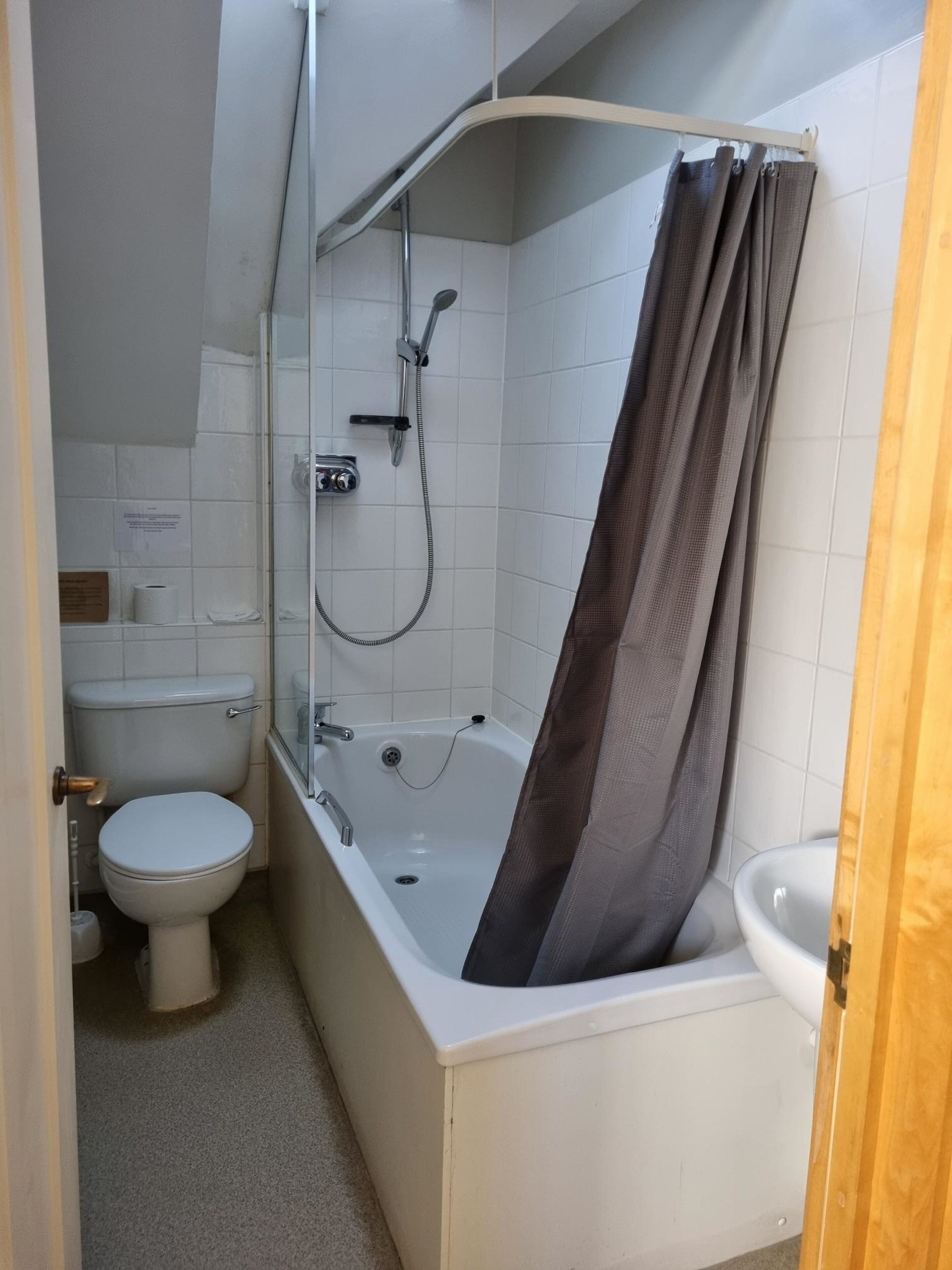A small, clean bathroom with a toilet, a shower, and a sink.