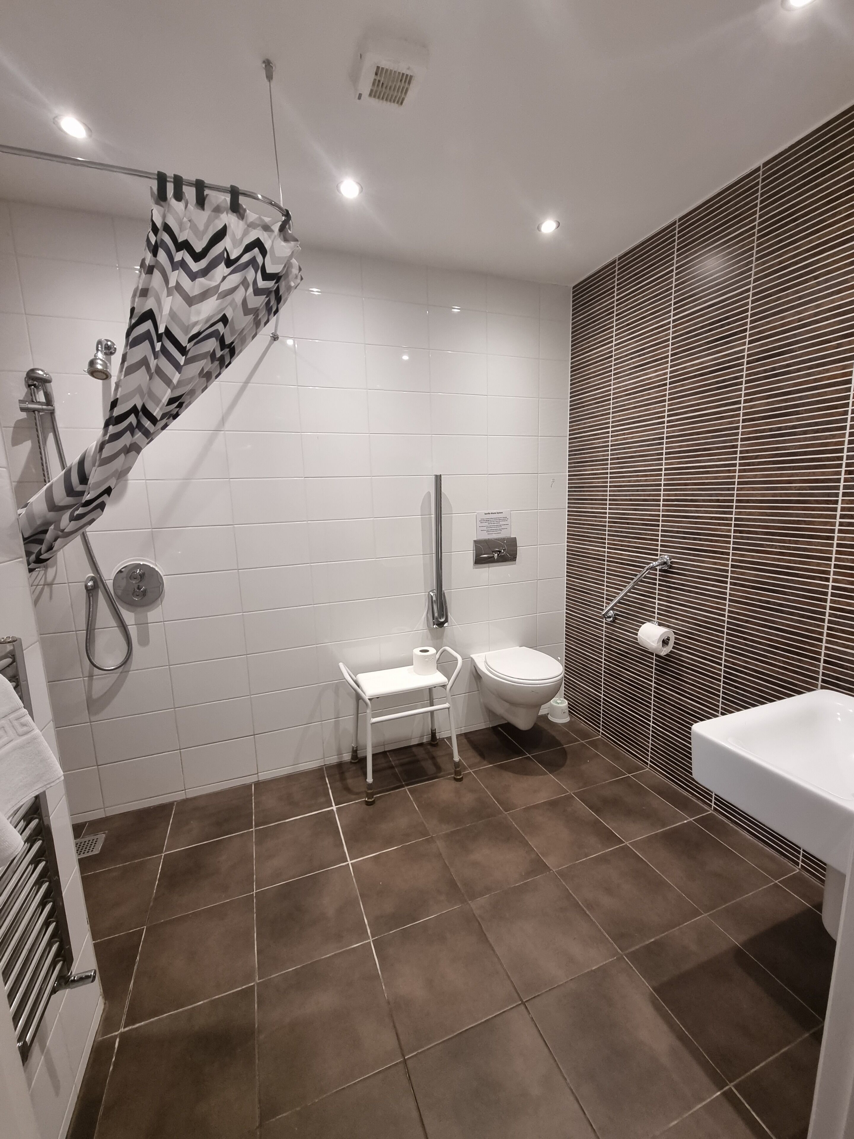 A modern bathroom with a shower, toilet, and sink.