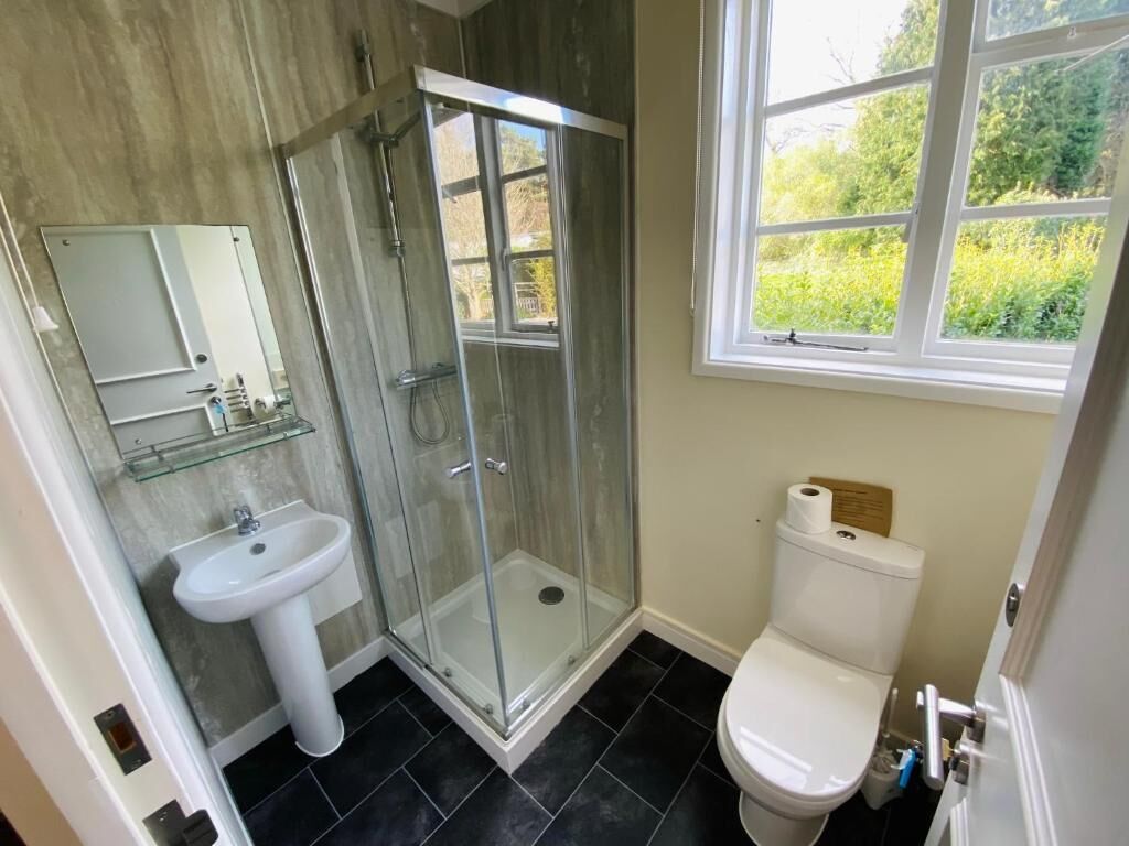Un bagno con box doccia in vetro, un lavandino bianco e un water.