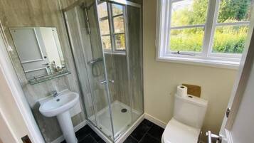 Un bagno con box doccia in vetro, un lavandino bianco e un water.