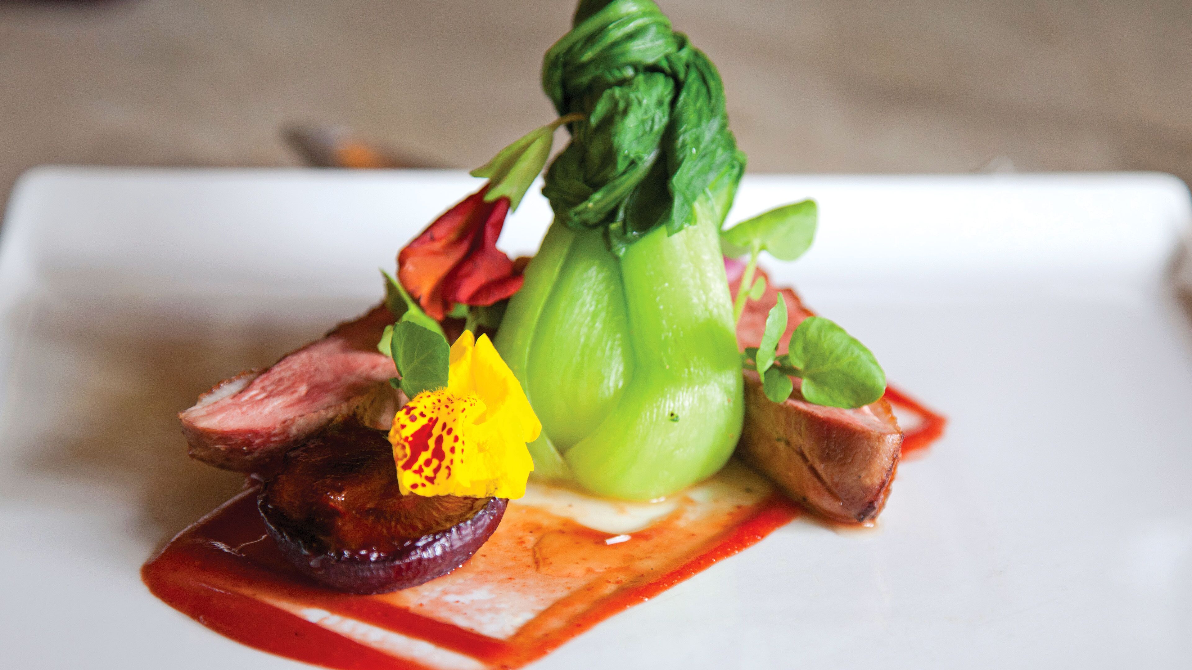 A dish with various vegetables and meat on a white plate.