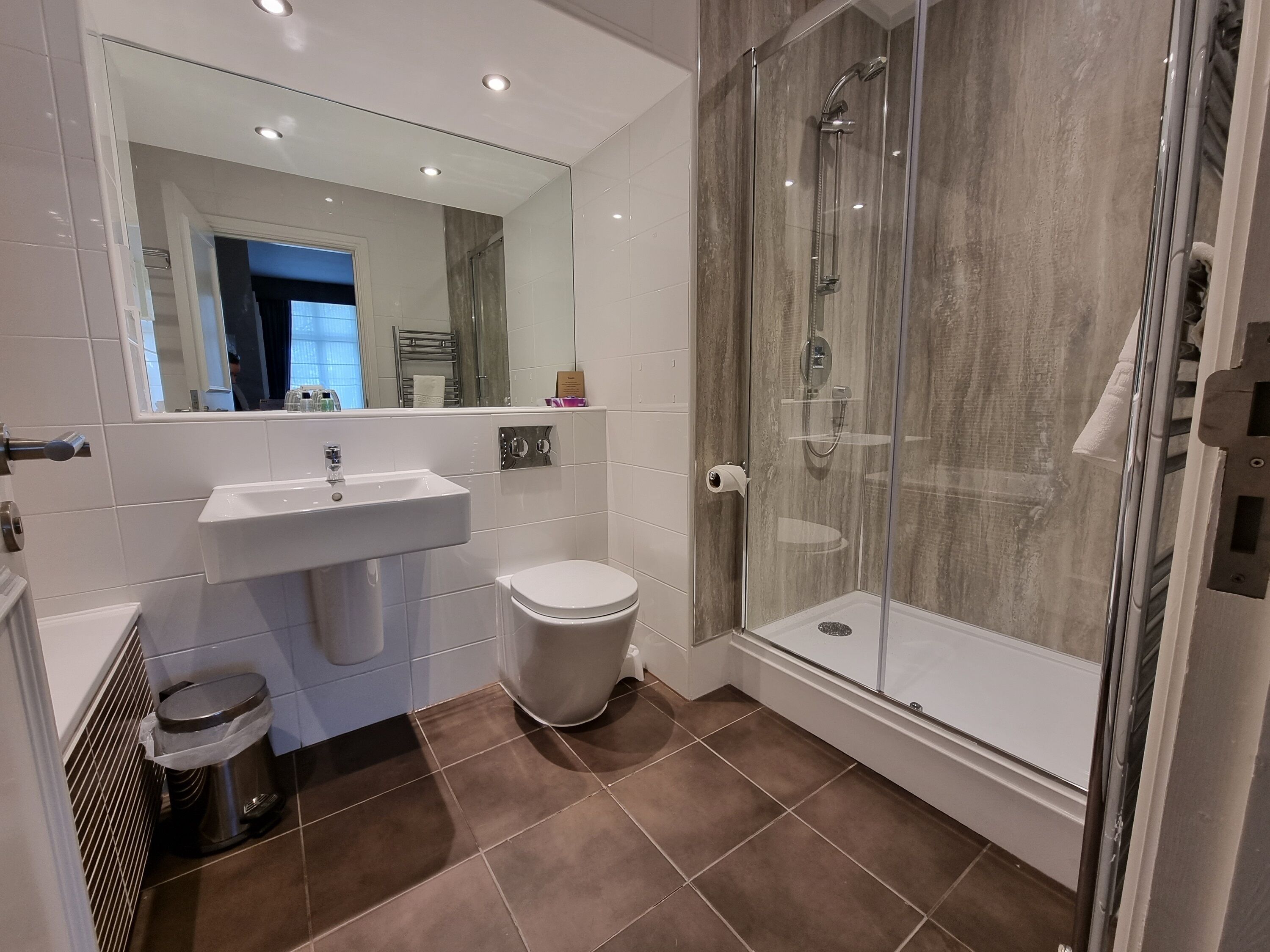 Een moderne badkamer met een douchecabine van glas, een wastafel en een toilet.