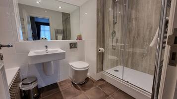 A modern bathroom with a glass-enclosed shower, a sink, and a toilet.