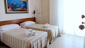 A hotel room with two beds, striped bedding, a painting of an underwater scene, a telephone, and a door. - Hotel Staccoli (Rimini)