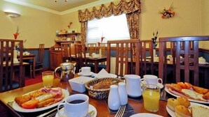 A breakfast setting with a table set for two, including plates of food, cups, a pitcher, and a basket of bread. - Atlantic View (Galway)